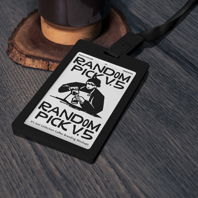Black ID badge card with dark green lanyard lying flat on a textured wooden surface next to a coffee grinder base, top angle flat lay mockup for cafe branding