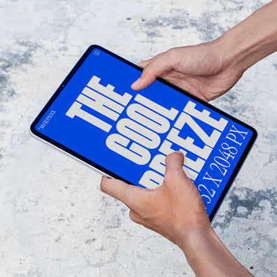 A person is holding an ipad labeled "THE COOL BREEZE 2732X2048 PX" in bold white text. Design by Mockup Flock