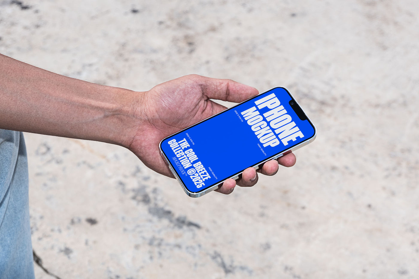 A person is holding an iPhone that says "IPHONE MOCKUP THE COOL BREEZE COLLECTION @2025" in bold white text. Design by Mockup Flock