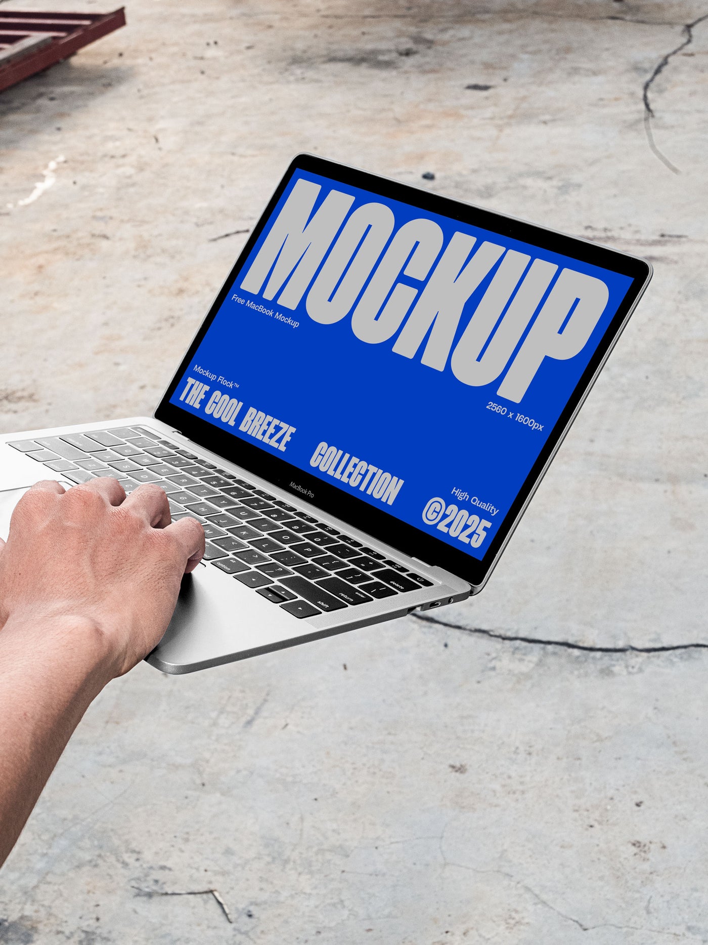 A person is holding an Macbook Device that says "MOCKUP THE COOL BREEZE COLLECTION @2025" in bold white text. Design by Mockup Flock