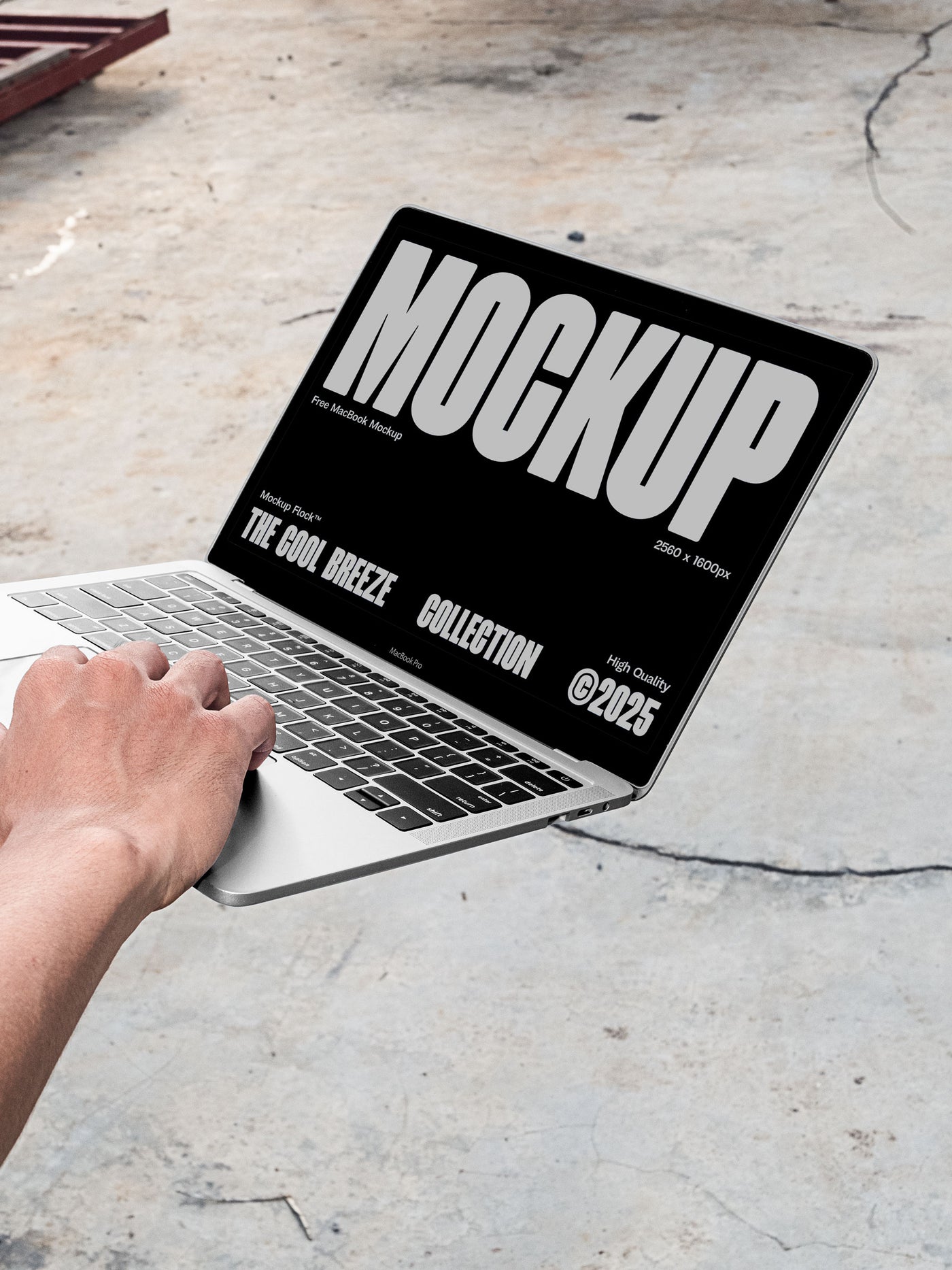 A person is holding an Macbook Device that says "MOCKUP THE COOL BREEZE COLLECTION @2025" in bold white text. Design by Mockup Flock
