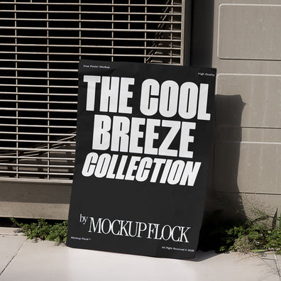 A black Poster with white text reading THE COOL BREEZE COLLECTION BY MOCKUP FLOCK is lying on the grassy floor, attached to the outdoor air conditioner.