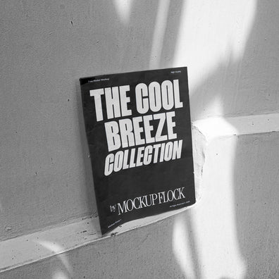 A black poster with white text reading THE COOL BREEZE COLLECTION BY MOCKUP FLOCK, against the wall.