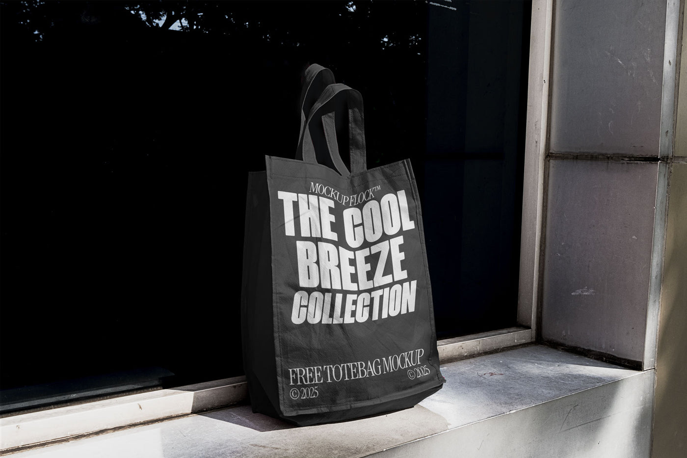 A black tote bag with white text reading THE COOL BREEZE COLLECTION BY MOCKUP FLOCK, is stuck to the window.