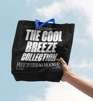 A person holds a tote bag that says "MOCKUP FLOCK THE COOL BREEZE COLLECTION FREE TOTE BAG MOCKUP" in bold text, on a blue sky background.