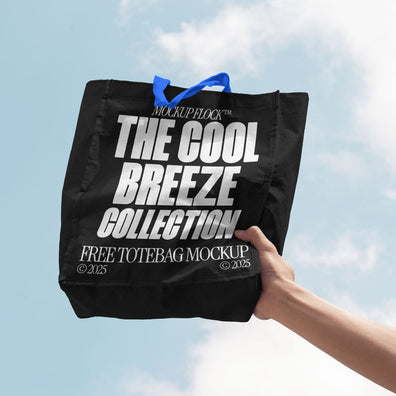 A person holds a tote bag that says "MOCKUP FLOCK THE COOL BREEZE COLLECTION FREE TOTE BAG MOCKUP" in bold text, on a blue sky background.