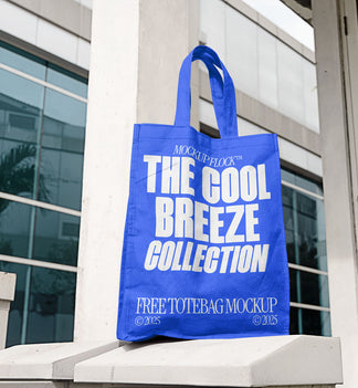 A blue tote bag with white text reading THE COOL BREEZE COLLECTION BY MOCKUP FLOCK