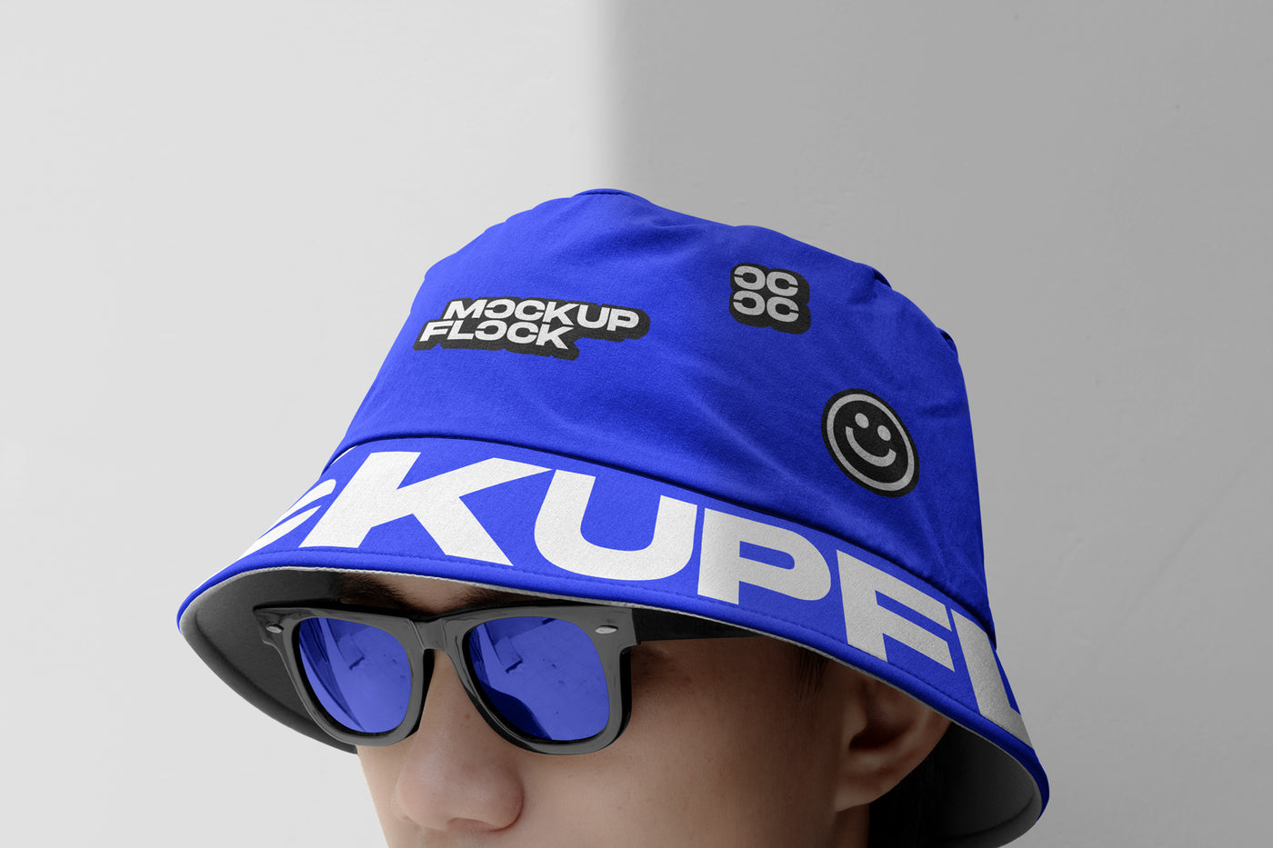 A person wearing a bucket hat and blue glasses, written MOCKUP FLOCK