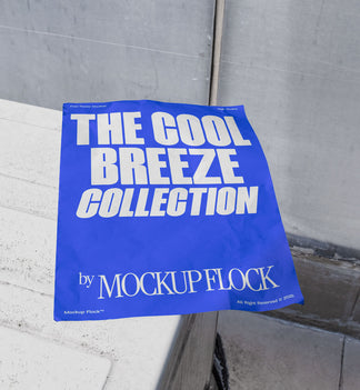 A blue Poster with white text reading THE COOL BREEZE COLLECTION BY MOCKUP FLOCK is lying on a box white, displayed in a outdoor setting.