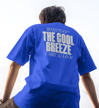A person wearing a t-shirt that says "MOCKUP FLOCK THE COOL BREEZE T-SHIRT: 31,5X45CM" in bold text, on a blue sky background.