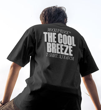 A person wearing a t-shirt that says "MOCKUP FLOCK THE COOL BREEZE T-SHIRT: 31,5X45CM" in bold text, on a blue sky background.