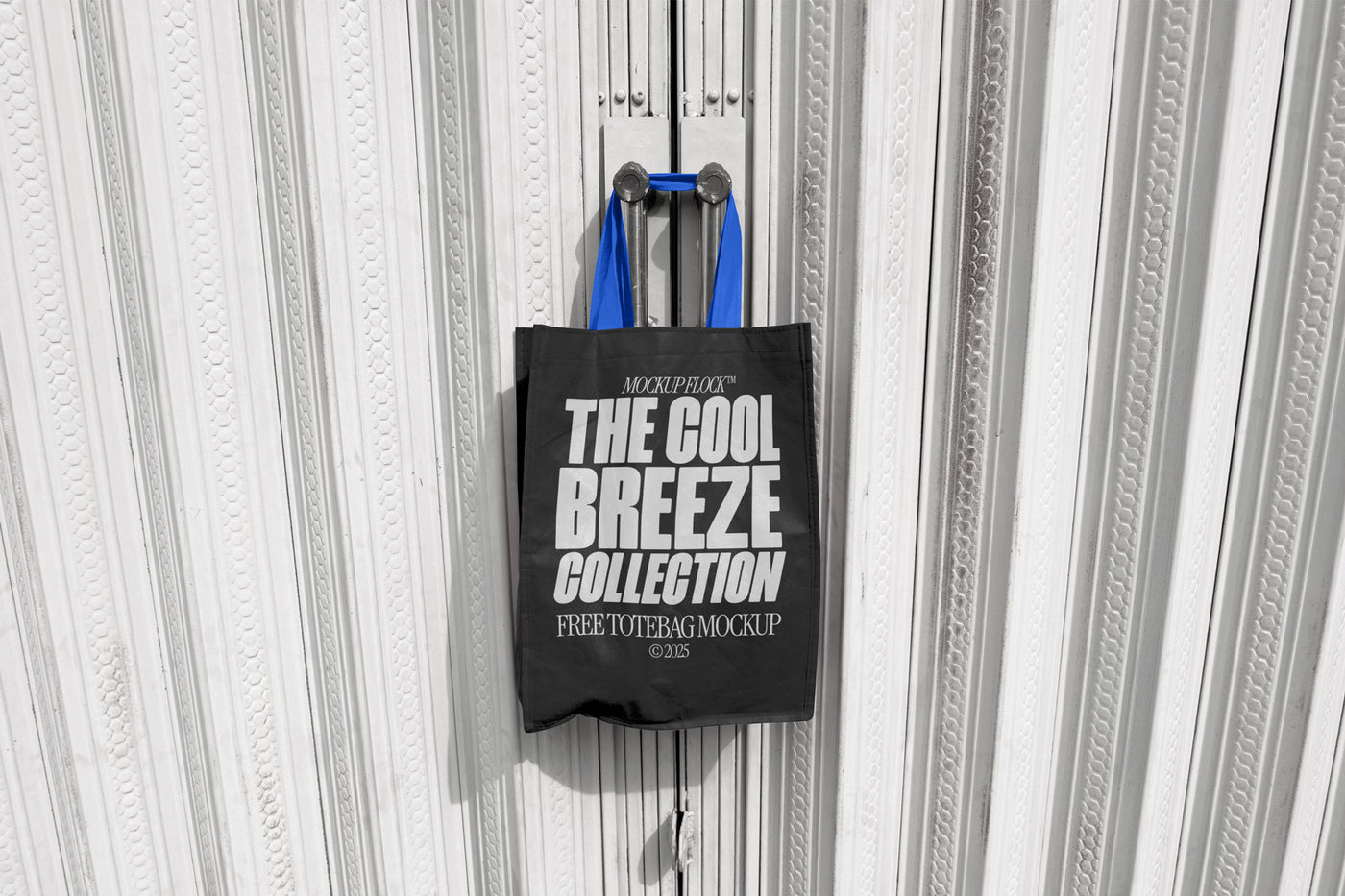A black tote bag with white text that reads "THE COOL BREEZE COLLECTION FREE TOTE BAG MOCKUP" hanging on a door handle.