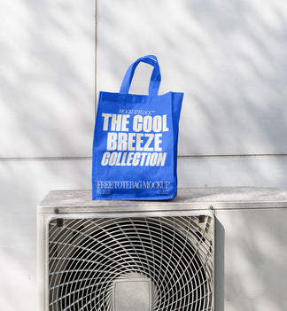 A blue Poster with white text reading "MOCKUP FLOCK THE COOL BREEZE COLLECTION FREE TOTE BAG MOCKUP" is lying on outdoor air conditioner.
