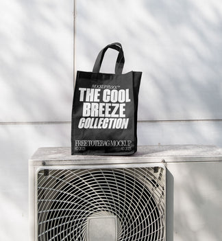 A black Poster with white text reading "MOCKUP FLOCK THE COOL BREEZE COLLECTION FREE TOTE BAG MOCKUP" is lying on outdoor air conditioner.