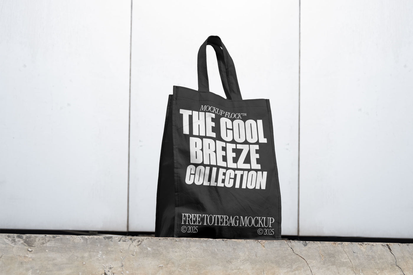 A black poster with white text reading THE COOL BREEZE COLLECTION BY MOCKUP FLOCK is lying on the floor, on a white wall background.