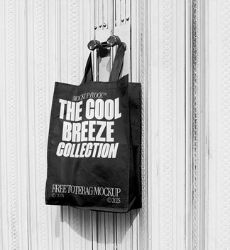 A black tote bag with white text that reads "THE COOL BREEZE COLLECTION FREE TOTE BAG MOCKUP" hanging on a door handle.