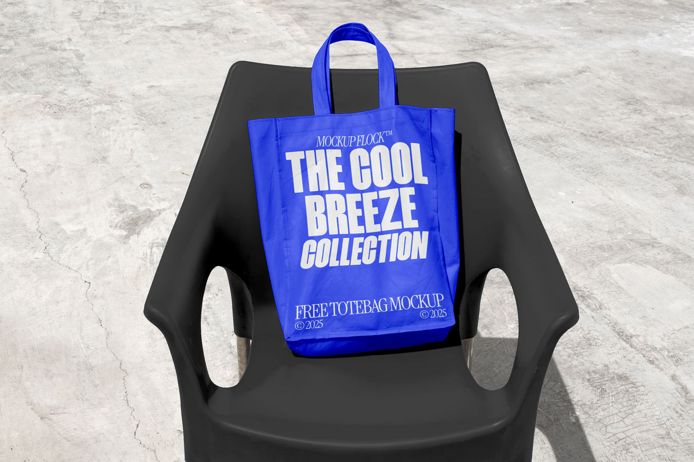 A blue Poster with white text reading "THE COOL BREEZE COLLECTION FREE TOTE BAG MOCKUP" is lying on black chair.