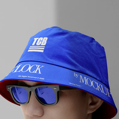 A person wearing a bucket hat and blue glasses, written TCB and MOCKUP FLOCK.