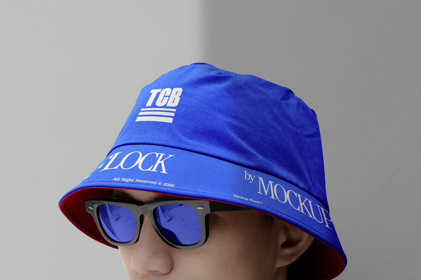 A person wearing a bucket hat and blue glasses, written TCB and MOCKUP FLOCK.