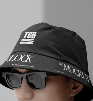 A person wearing a bucket hat and black glasses, written TCB and MOCKUP FLOCK.