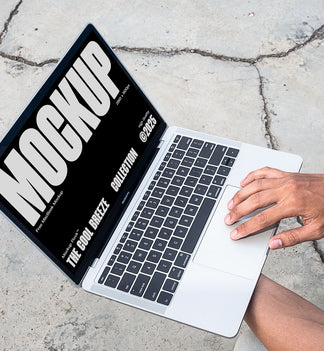 A person is holding an Macbook Device that says "MOCKUP THE COOL BREEZE COLLECTION @2025" in bold white text. Design by Mockup Flock