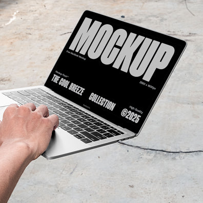 A person is holding an Macbook Device that says "MOCKUP THE COOL BREEZE COLLECTION @2025" in bold white text. Design by Mockup Flock