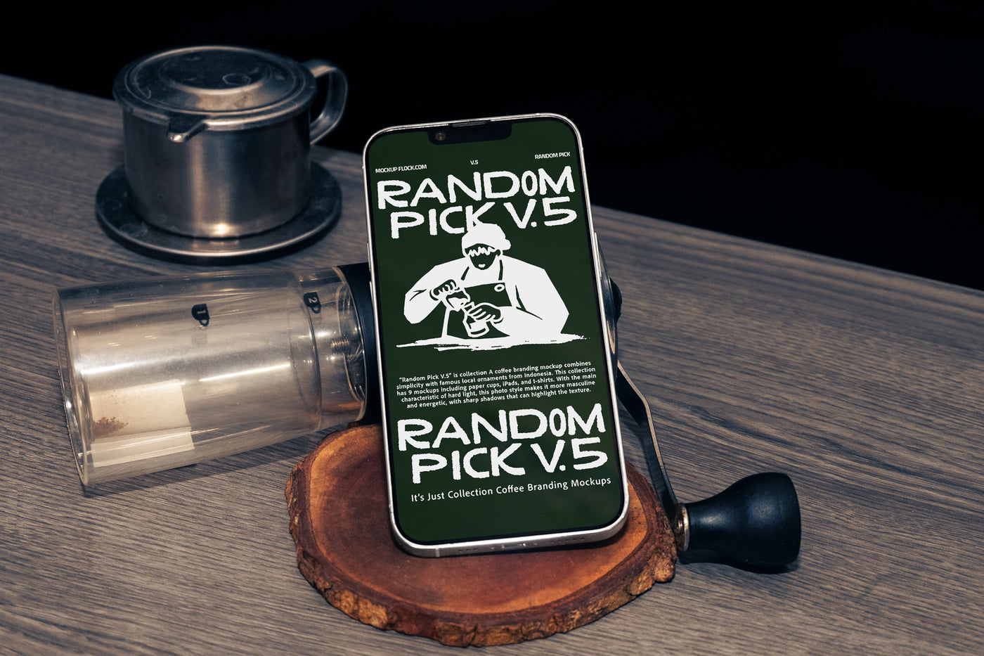 Green iPhone standing upright on a wood slice coaster surrounded by coffee props including a manual grinder and Vietnamese drip filter on a wooden table with dark background