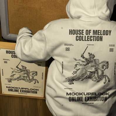 poster frame mockup features a person wearing a hoodie sitting next to a poster frame