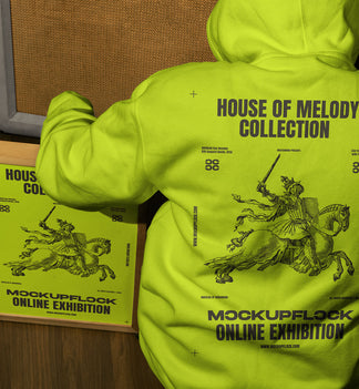 poster frame mockup features a person wearing a hoodie sitting next to a poster frame