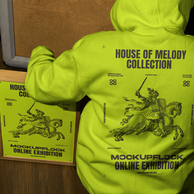 poster frame mockup features a person wearing a hoodie sitting next to a poster frame