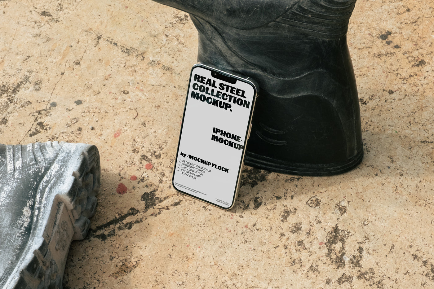 MockupFlock Real Steel Collection iPhone mockup leaning against a black rubber boot on a rough, dusty concrete floor, showcasing realistic lighting and industrial textures.