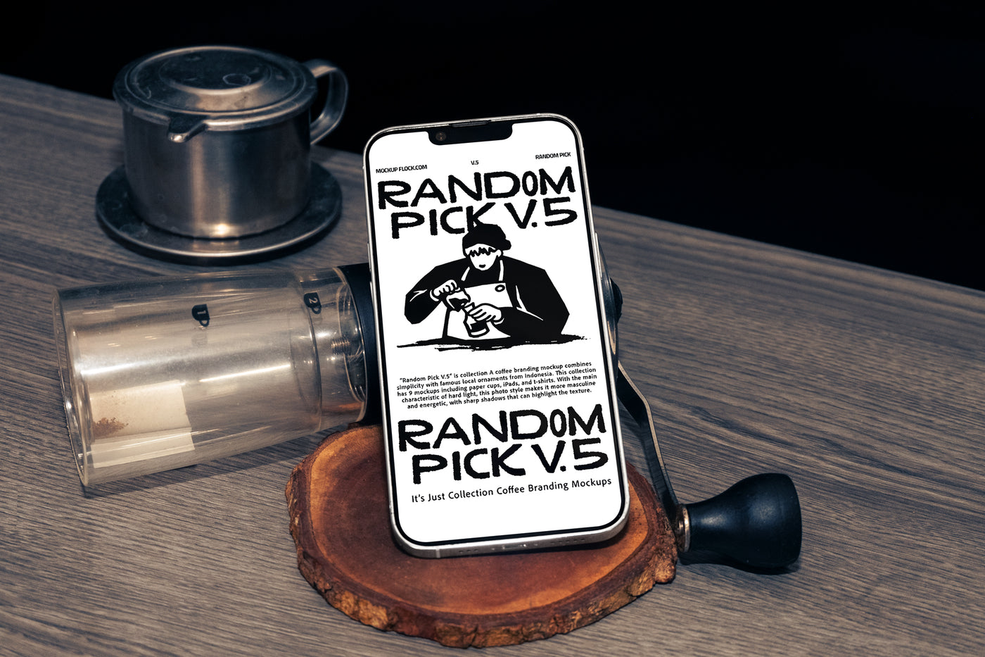 White iPhone standing upright on a wood slice coaster surrounded by coffee props including a manual grinder and Vietnamese drip filter on a wooden table with dark background