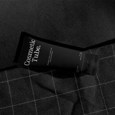 Cosmetic black tube mockup lying diagonally on orange fabric with checkered stitch pattern
