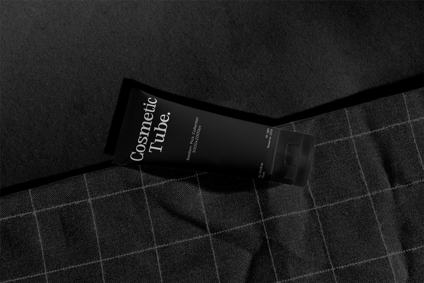 Cosmetic black tube mockup lying diagonally on orange fabric with checkered stitch pattern