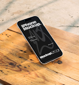 Flat lay view of a black iPhone mockup placed on a rustic wooden table under natural sunlight