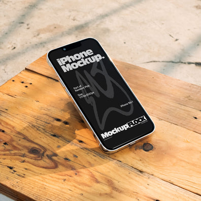 Flat lay view of a black iPhone mockup placed on a rustic wooden table under natural sunlight