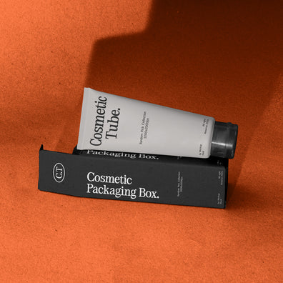 White cosmetic tube leaning on black packaging box mockup, terracotta studio backdrop