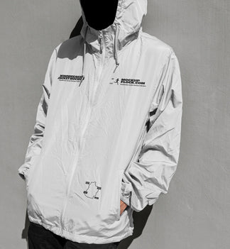 A white hooded windbreaker jacket mockup with black graphic prints on the chest, modeled on a black mannequin against a textured gray wall.