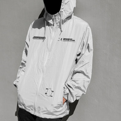 A white hooded windbreaker jacket mockup with black graphic prints on the chest, modeled on a black mannequin against a textured gray wall.