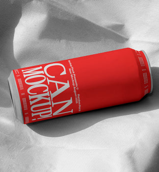 Red beverage can lying on wrinkled white fabric with dramatic shadow, minimal studio mockup
