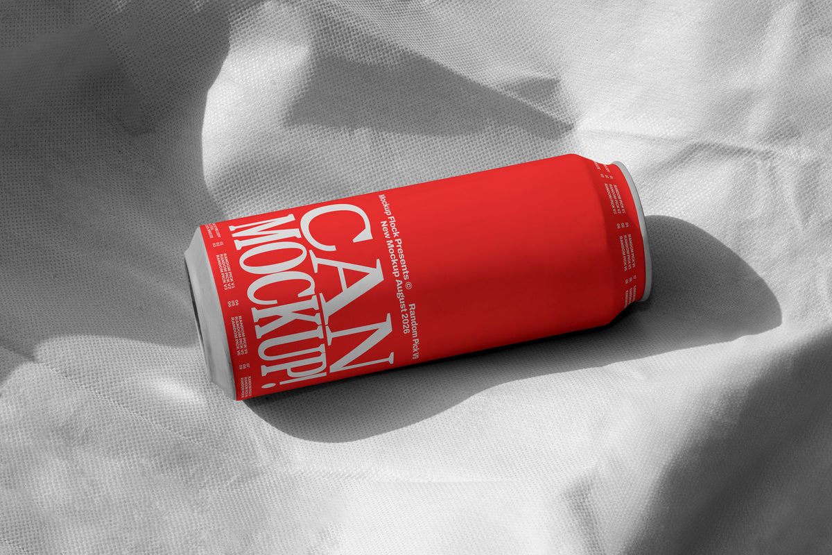 Red beverage can lying on wrinkled white fabric with dramatic shadow, minimal studio mockup