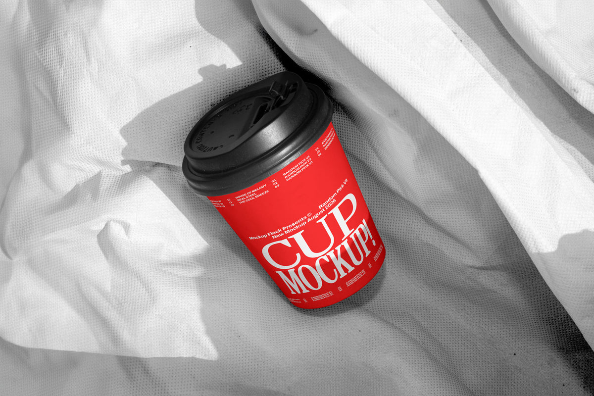 Red paper coffee cup mockup with black lid on wrinkled white fabric, minimal studio mockup