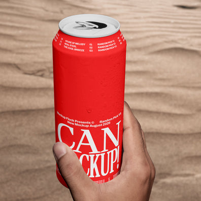 Hand holding a red beverage can mockup upright against a sand dune background, lifestyle mockup