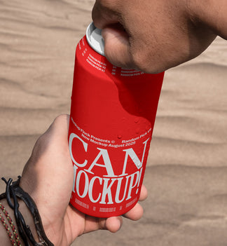 Close-up of hands opening a red beverage can mockup outdoors with desert sand background, lifestyle mockup