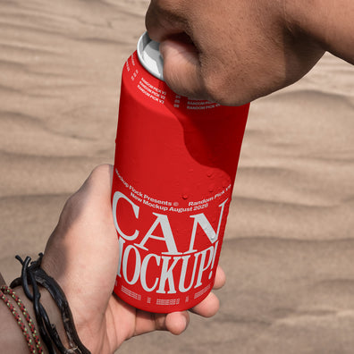 Close-up of hands opening a red beverage can mockup outdoors with desert sand background, lifestyle mockup