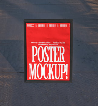 Black framed poster mockup standing upright on a dark textured metal floor with soft shadow overlay