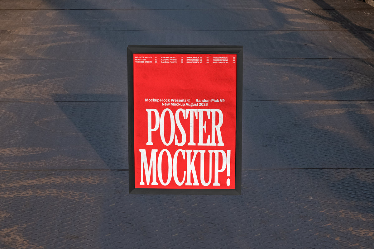 Black framed poster mockup standing upright on a dark textured metal floor with soft shadow overlay