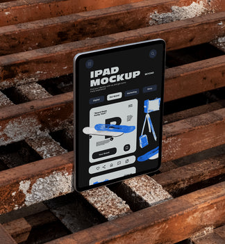 iPad standing upright on rusty industrial metal pallets outdoors displaying app UI design, dark urban industrial style photography