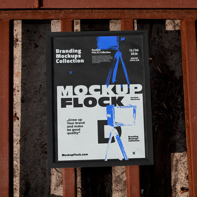 Framed poster mockup mounted on a rusty industrial metal fence outdoors in bright sunlight, bold black and white design with blue accents, urban street style branding