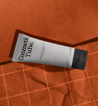 Cosmetic white tube mockup lying diagonally on orange fabric with checkered stitch pattern